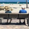 Idosos sentados em banco na praia