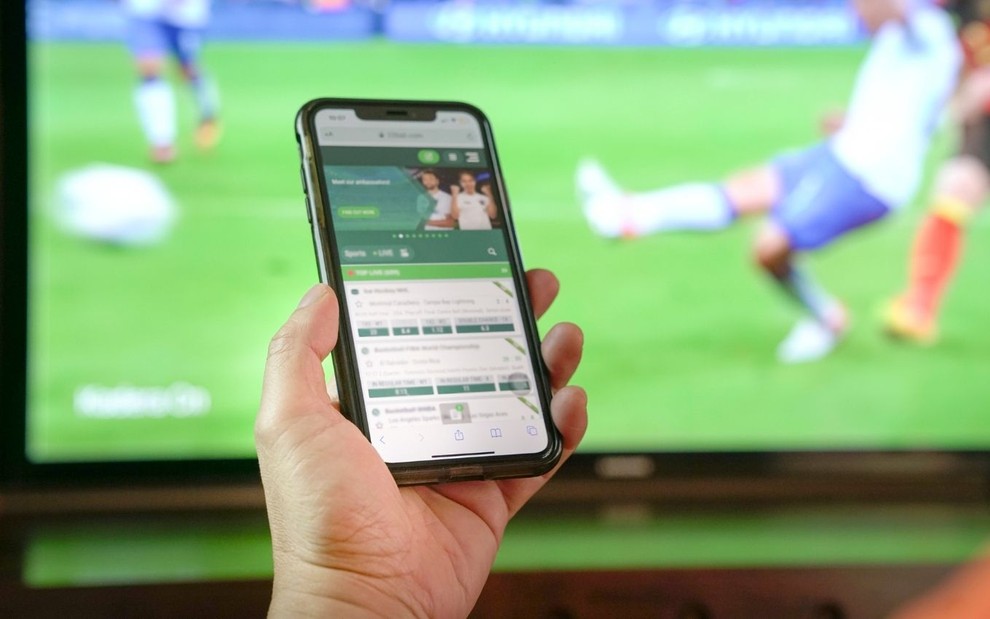Imagem de pessoa acessa site de apostas esportivas durante jogo