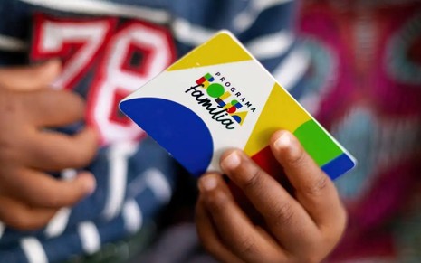 Criança segura cartão do Bolsa Família