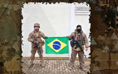 Dois soldados em pé segurando a bandeira do Brasil