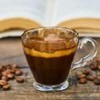 Imagem de café preto e grãos de café espalhados em mesa