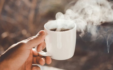 Pessoa segurando xícara de café quente