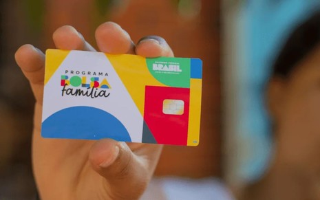 Mulher segura cartão do Bolsa Família