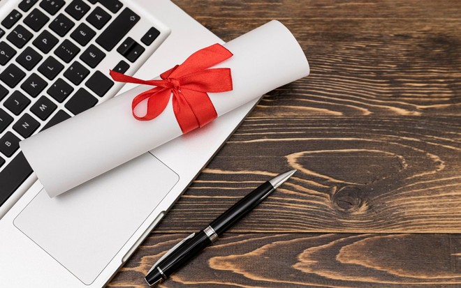Certificado com fita em cima do notebook