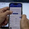 Mãos segurando um celular no site Meu INSS