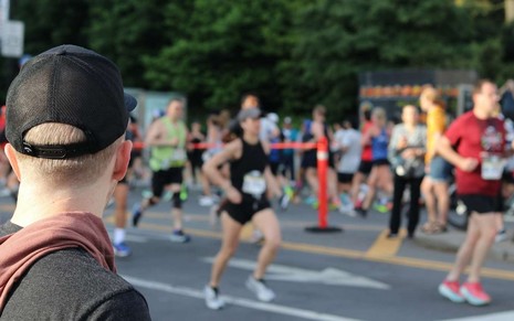 Homem observa pessoas em corrida de rua