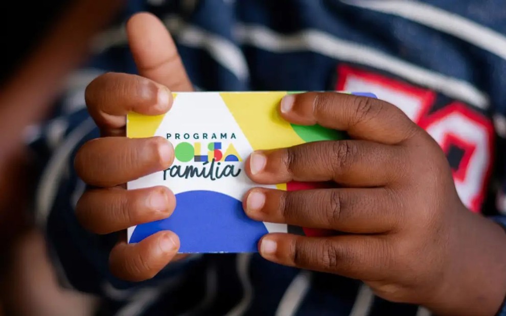 Menino segurando cartão do Bolsa Família