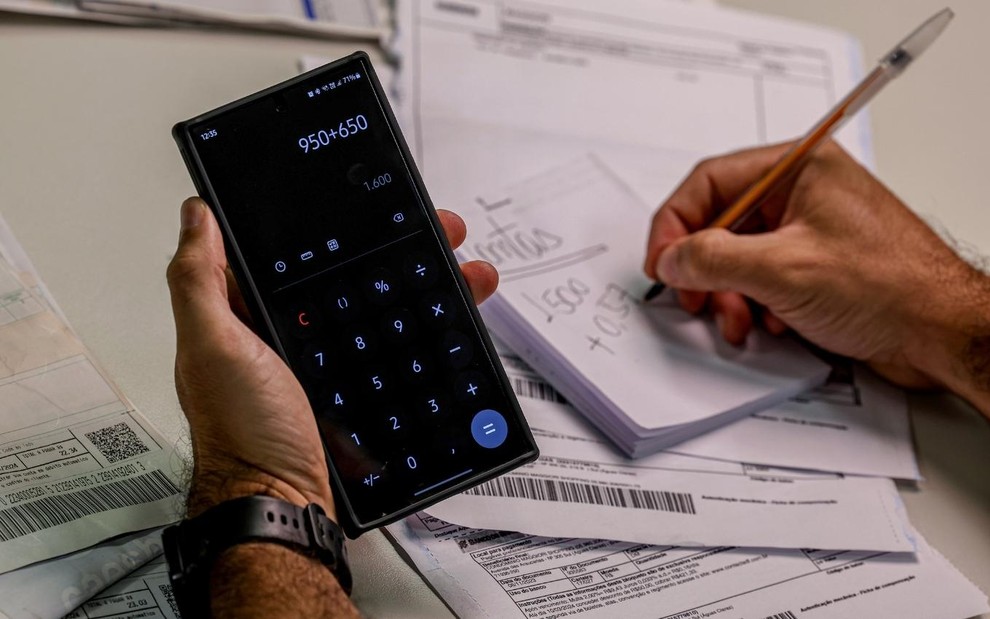 Homem segura telefone com calculadora aberta