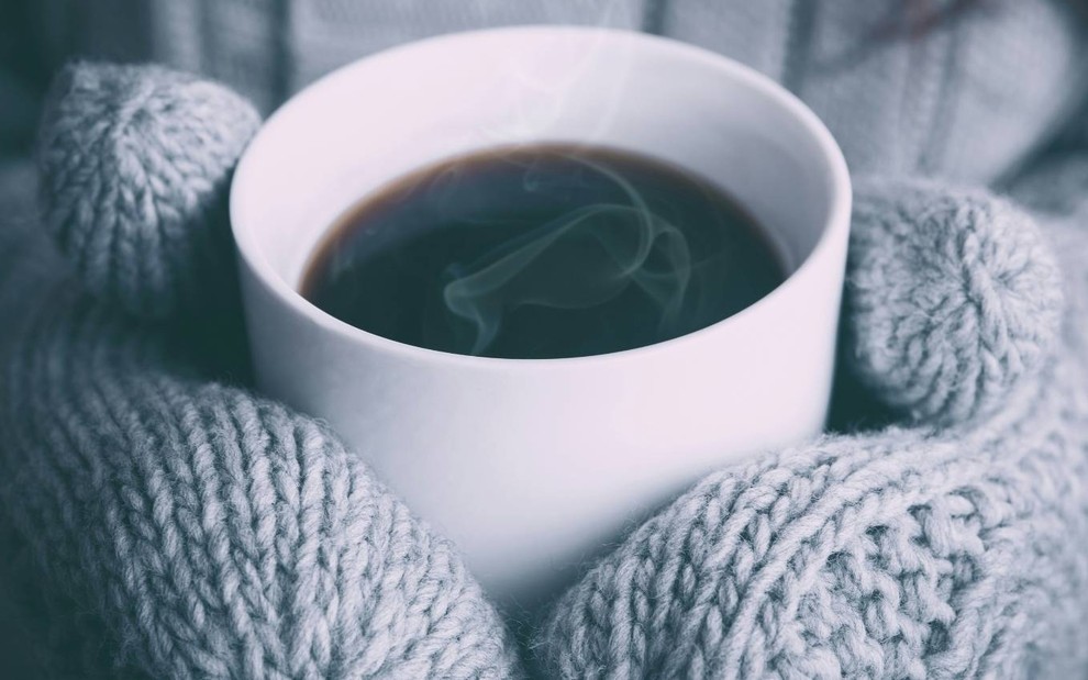 Pessoa com luvas segura café quente