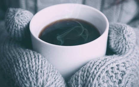 Pessoa com luvas segura café quente