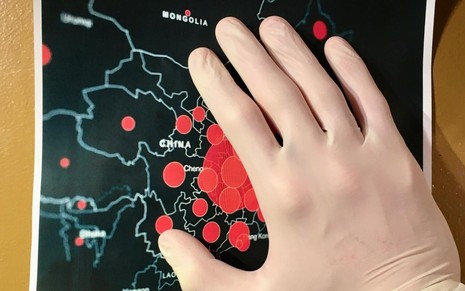 Mão vestindo luva branca posicionada em um mapa