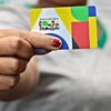 Mulher segura cartão do Bolsa Família