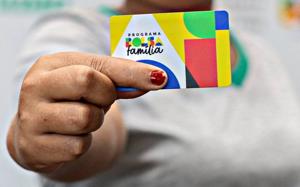 Mulher segura cartão do Bolsa Família