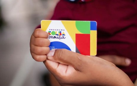 Um adulto e um bebe segurando o cartão do bolsa família