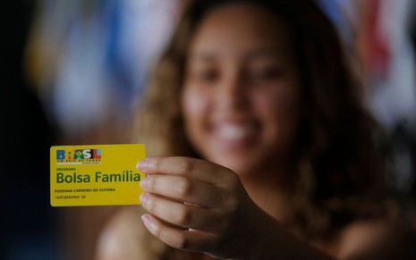 Mulher segurando o cartão do bolsa família