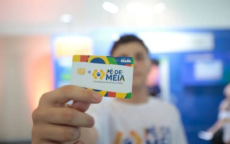 Rapaz segurando o cartão do  Pé-de-Meia