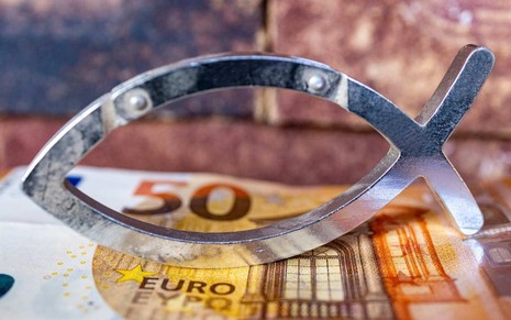 Tesoura em formato de peixe em cima de cédula de euro