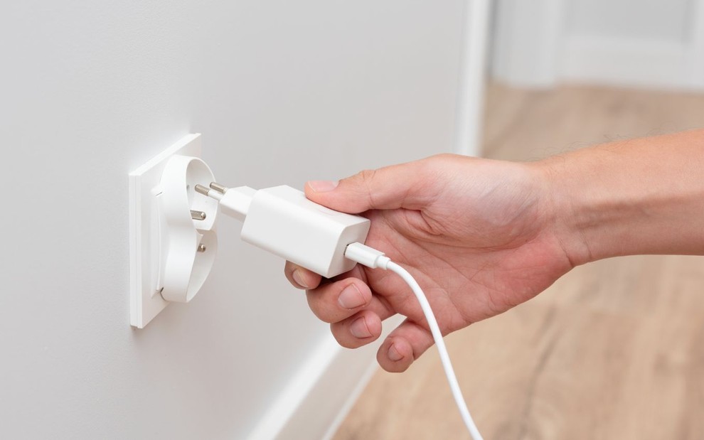 Pessoa colocando o carregador na tomada