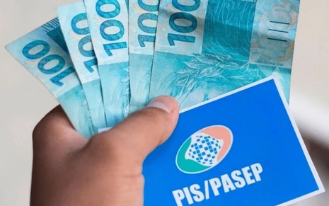 Homem segura notas de 100 reais e um documento escrito PIS/Pasep