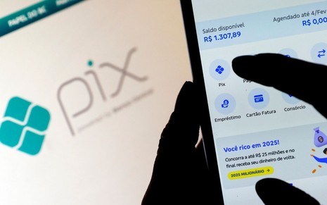 Mão segurando celular enquanto transferência Pix é realizada
