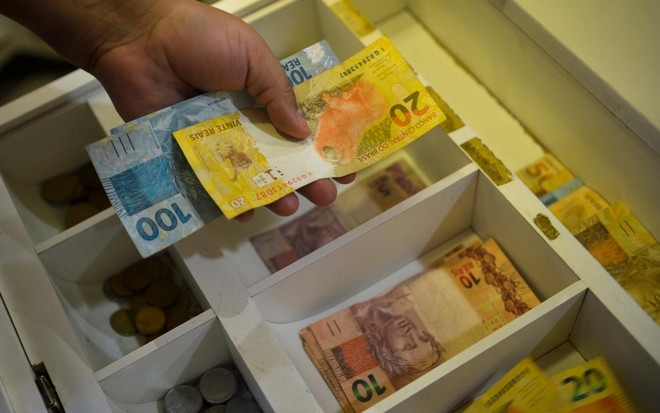 Imagem de pessoa contando cédulas de dinheiro