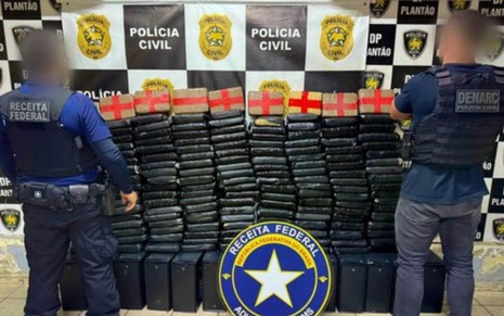 Policiais em pé em frente as drogas