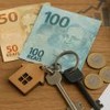 Chaves de imóvel sobre notas de real representam impacto tributário (imagem gerada por IA).