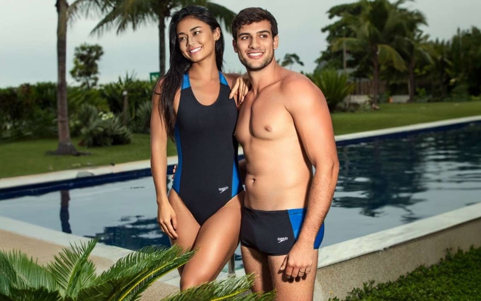 Imagem de um casal na frente de uma piscina com roupas de banho