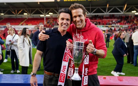 Imagem de Rob McElhenney e Ryan Reynolds comemorando juntos vitória do Wrexham