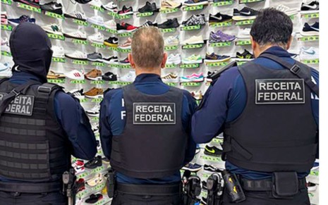 Três policiais em frente a prateleira com tênis