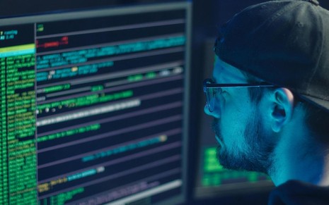 Homem escreve códigos no computador