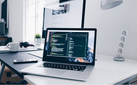 Imagem de notebook sobre a mesa com tela de programação