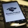 Celular ligado com a tela da Receita Federal