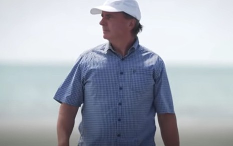 Homem de camisa e boné na praia